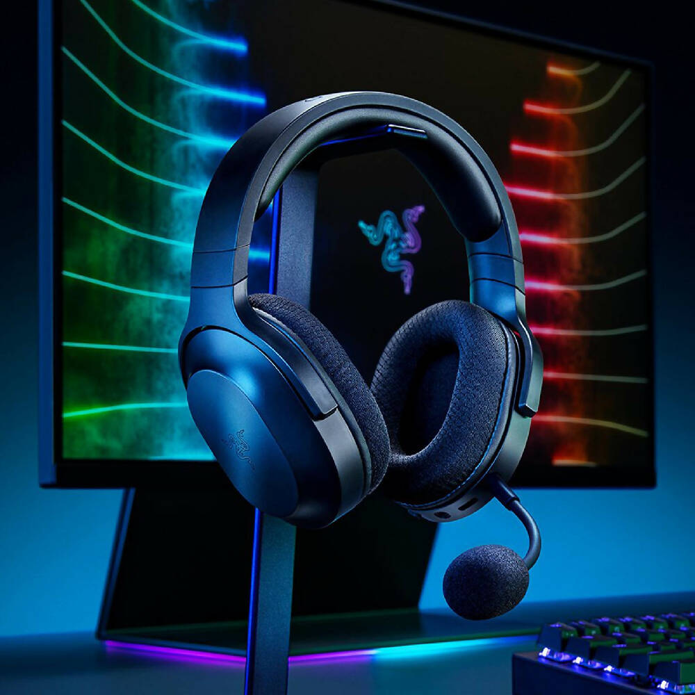 Razer Barracuda X Wireless Headset Black three quarter view with miic on stand and infront of colour monitor